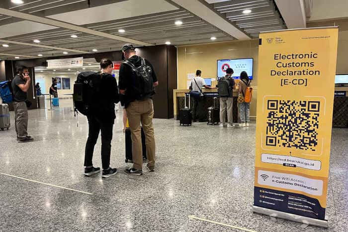 Airport sign about the Electronic Customs Declaration (e-CD) with people waiting